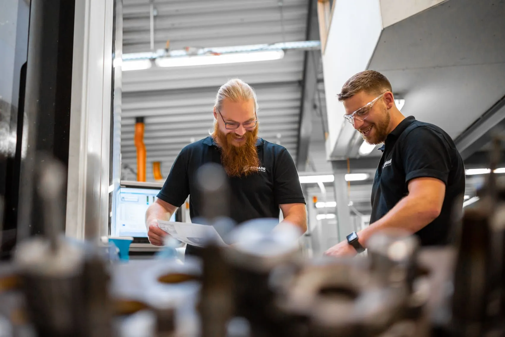 Zwei Mitarbeiter der Schade GmbH prüfen ein Bauteil in der Fertigung