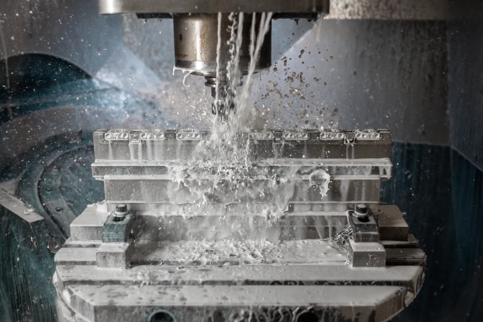 CNC-Fräse bei der Schade GmbH, Kühlflüssigkeit spritzt über das Werkstück