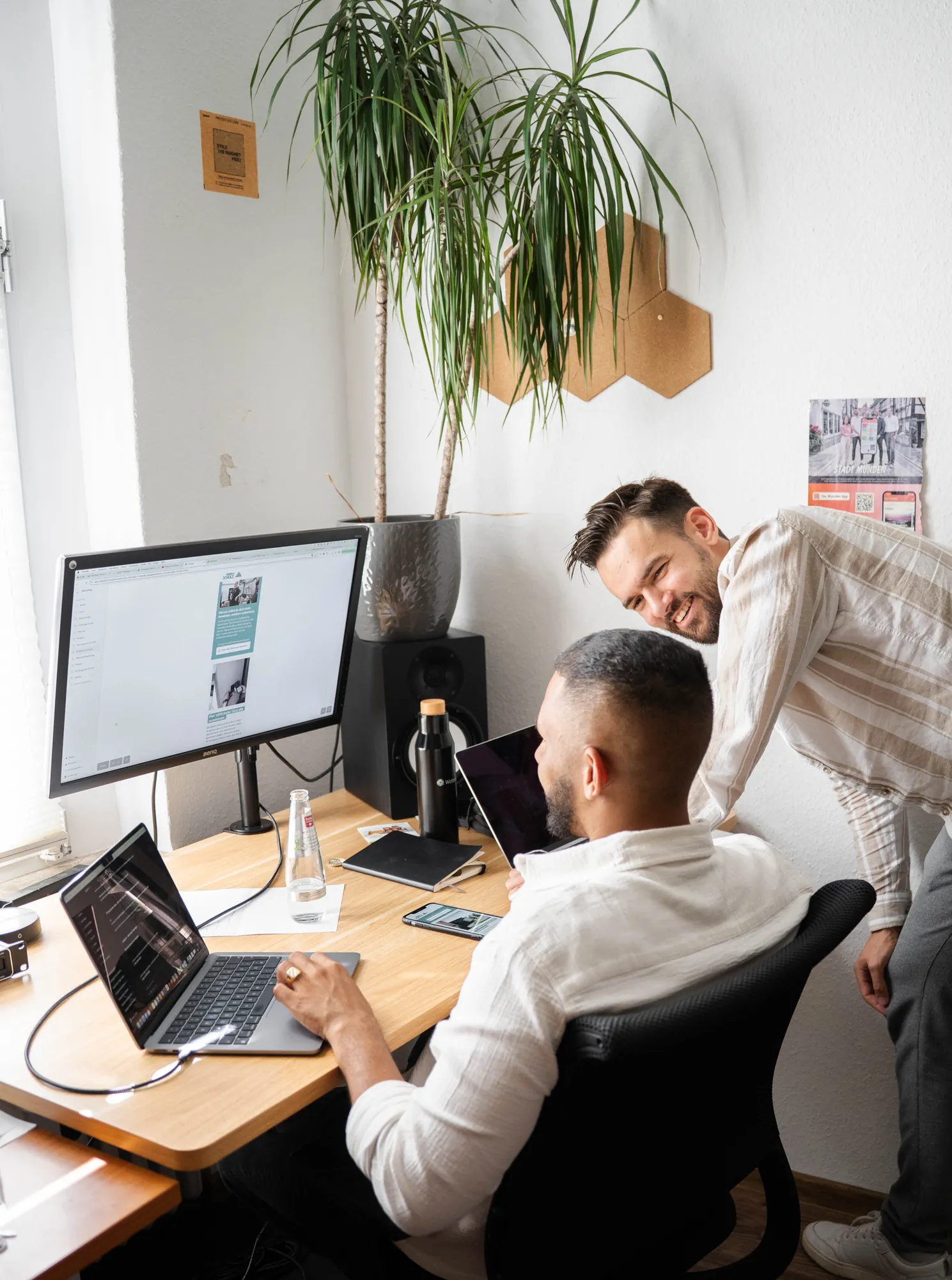 Micha und ein Kollege lachen gemeinsam am Schreibtisch im sorum-Büro