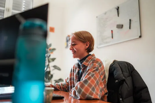 Eine Kollegin von sorum lacht am Schreibtisch im Büro in Hann. Münden